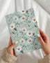 A5 grandmacore journal, sage-blue cover with white daisies and wildflowers"